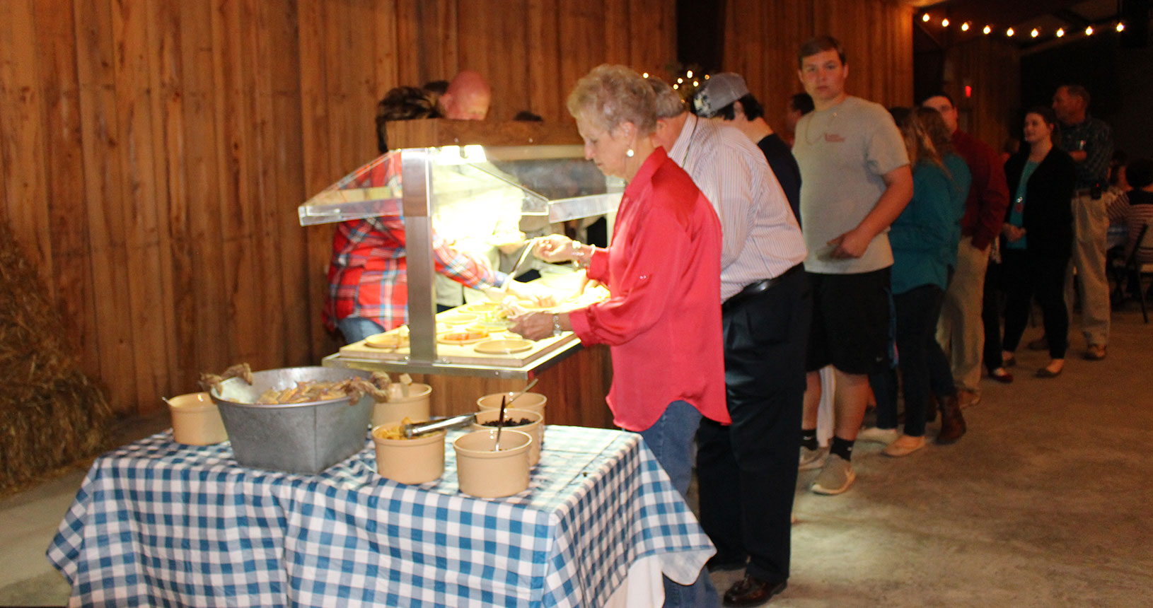 A woman in red shirt standing next to food.