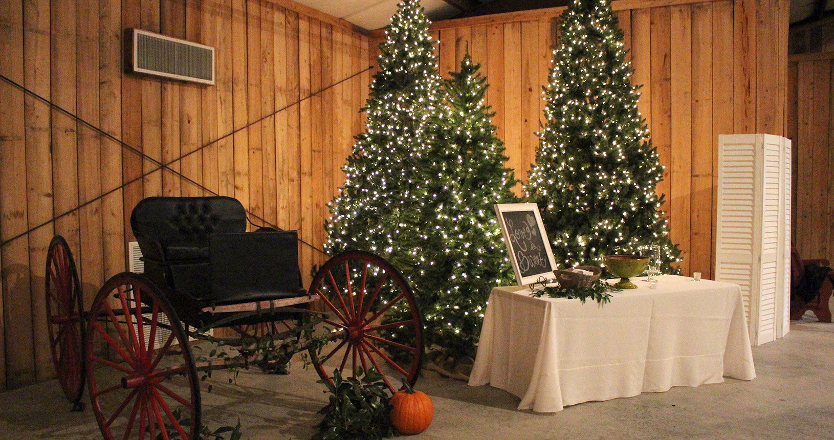 A room with two christmas trees and a wagon wheel.